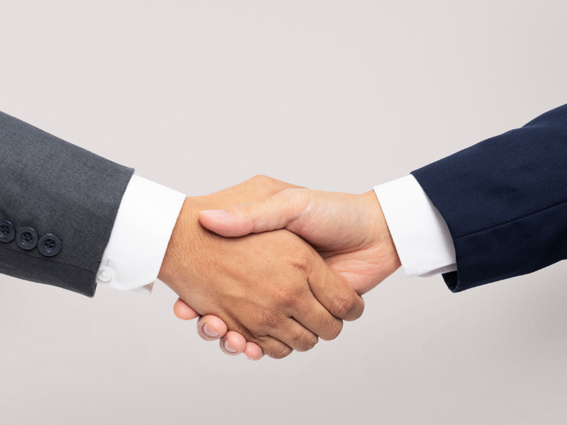 A imagem mostra duas pessoas apertando as mãos, representando um acordo ou parceria de negócios.